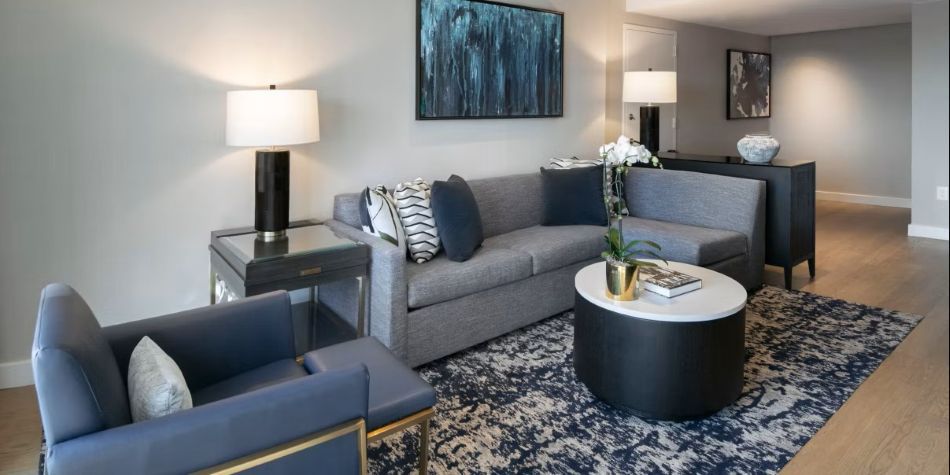 Compass Suite living room with L-shaped sofa, blue armchair, and abstract blue artwork.