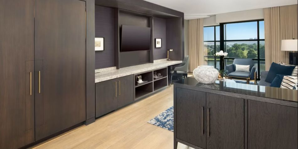 Compass Suite living and work area with built-in entertainment unit, desk nook, and water views.
