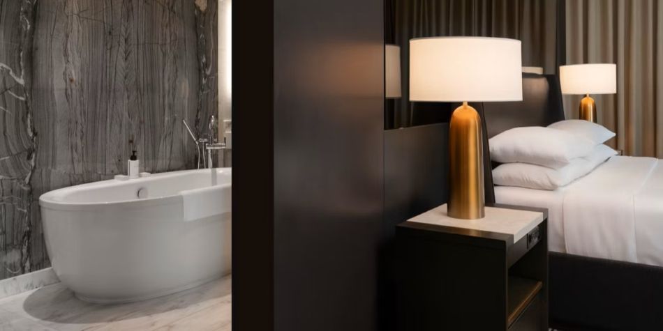 Constellation Suite bedroom open to bathroom with freestanding tub and marble accent wall.