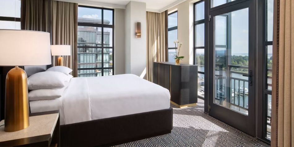 Constellation Suite bedroom with king bed, gold lamp, and balcony access to water views.