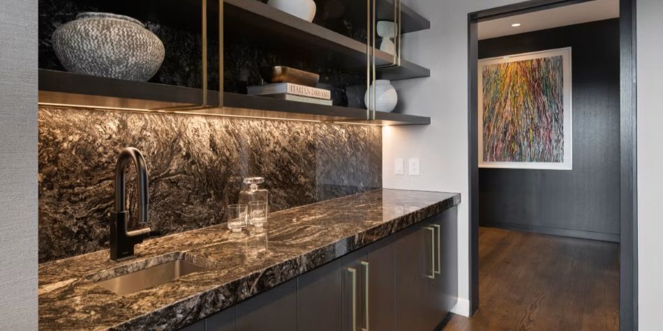 Constellation Suite wet bar with dark cabinetry, marble counter, and brass shelving.