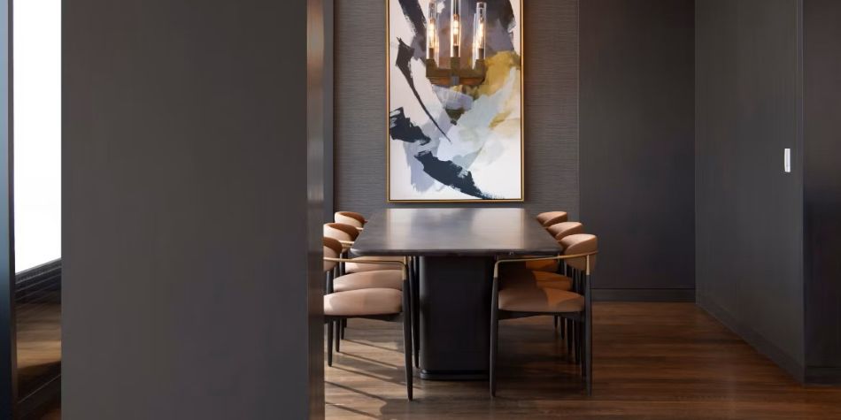 Constellation Suite formal dining room with pedestal table, upholstered chairs, and abstract art.