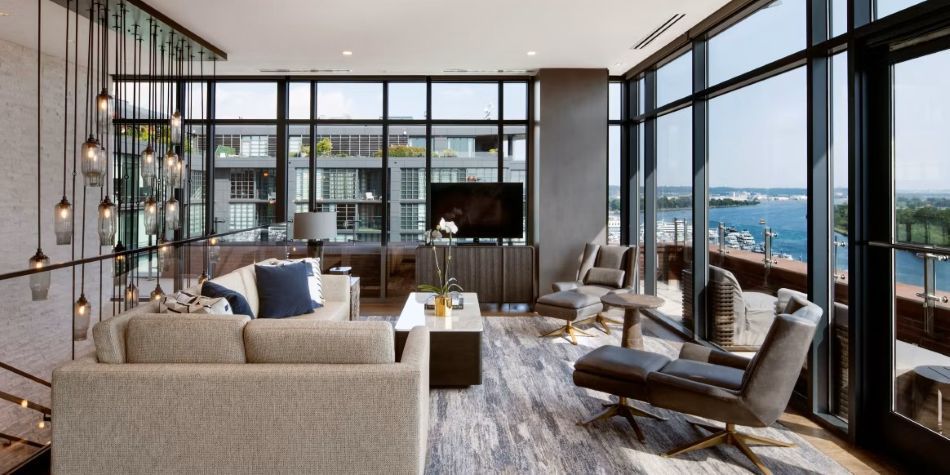 Constellation Suite living room with sectional sofa, marble coffee table, and panoramic river views.