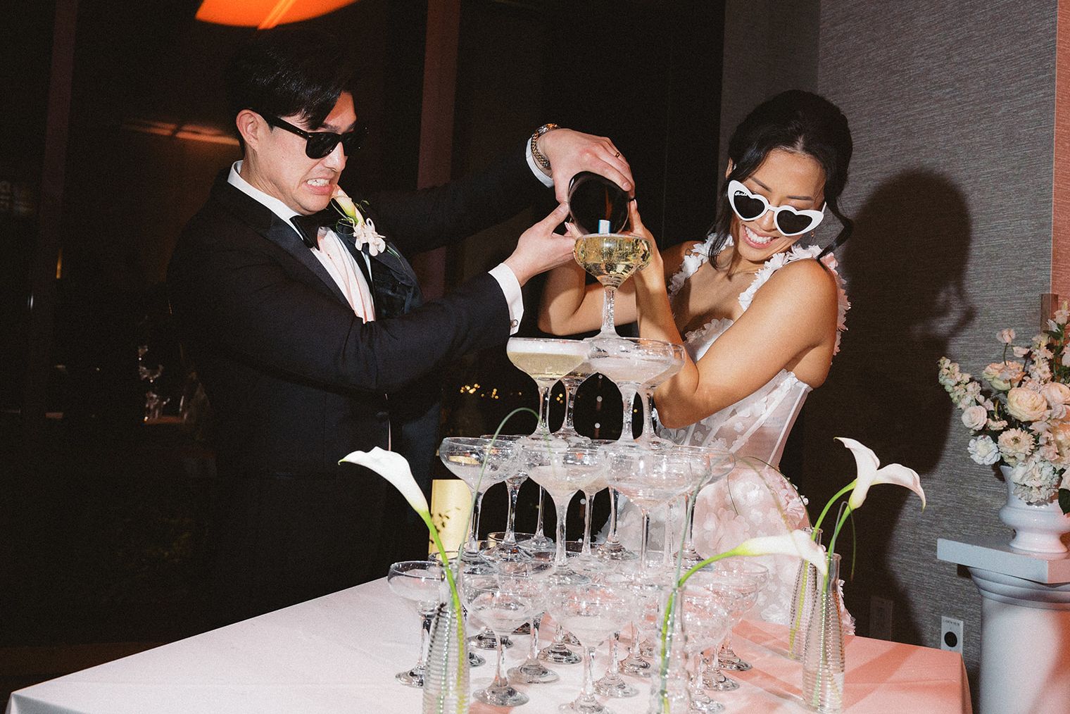 Couple pouring a champagne tower at a wedding celebration