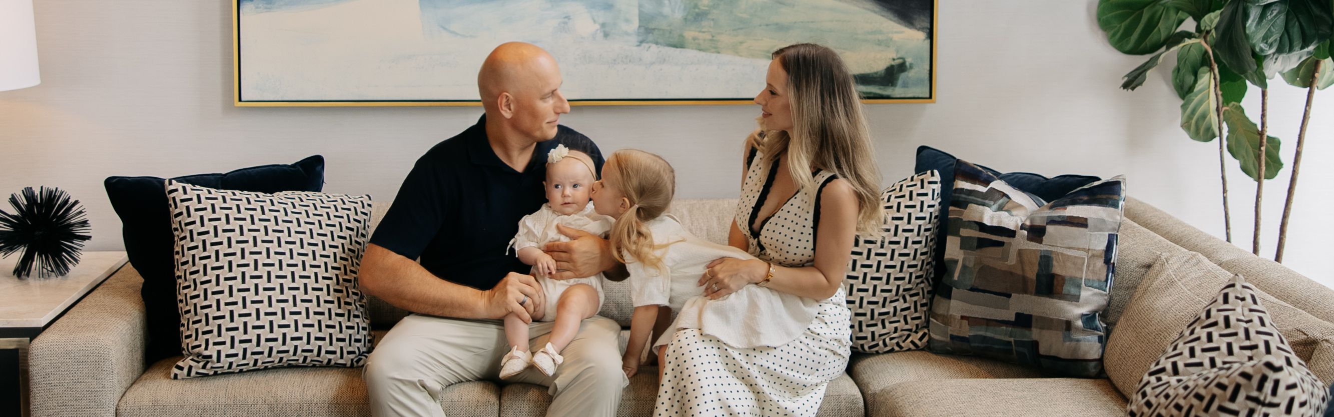 Family seated together in a spacious hotel lounge with contemporary furnishings, artwork, and floor-to-ceiling ceilings creating a welcoming gathering space.