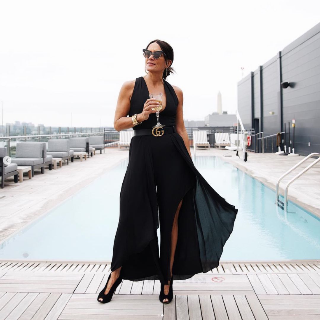fashionable woman posing on pool deck holding cocktail
