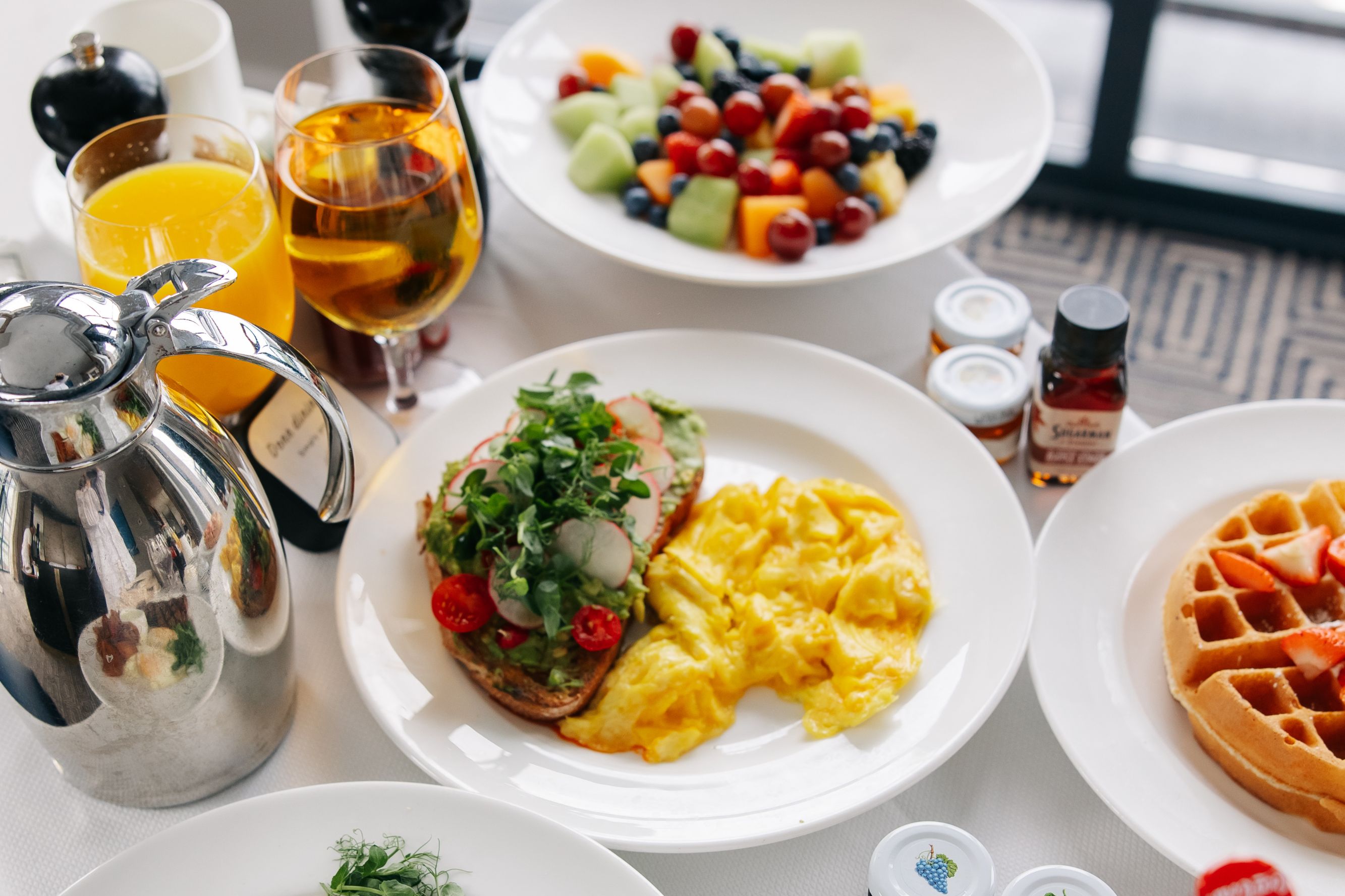 In-room breakfast with avocado toast, waffle, and fresh fruit