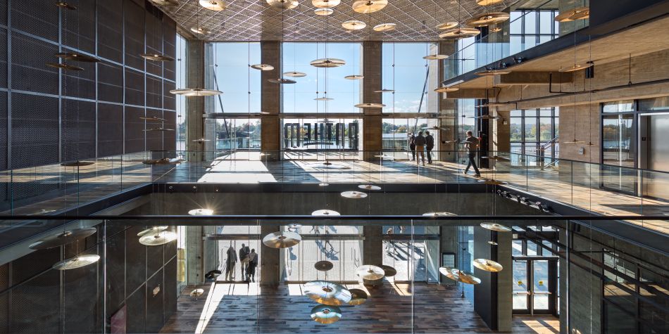 Multi level view of the interior of The Anthem, showing ground and second floor, cymbal chandelier, and visitors during the day.