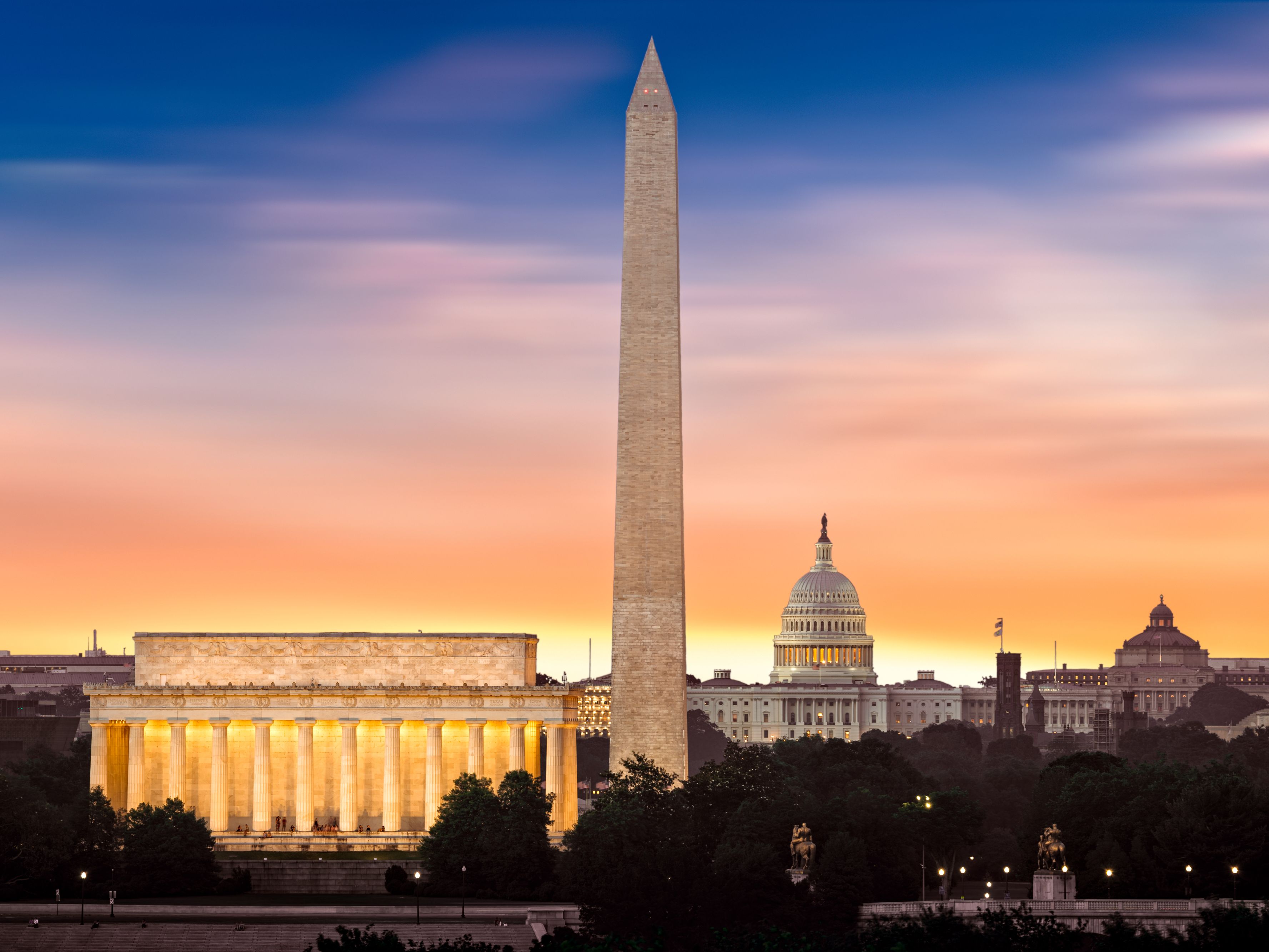 Washington Monument, Lincoln Memorial, and U.S. Capitol at sunset along the National Mall.