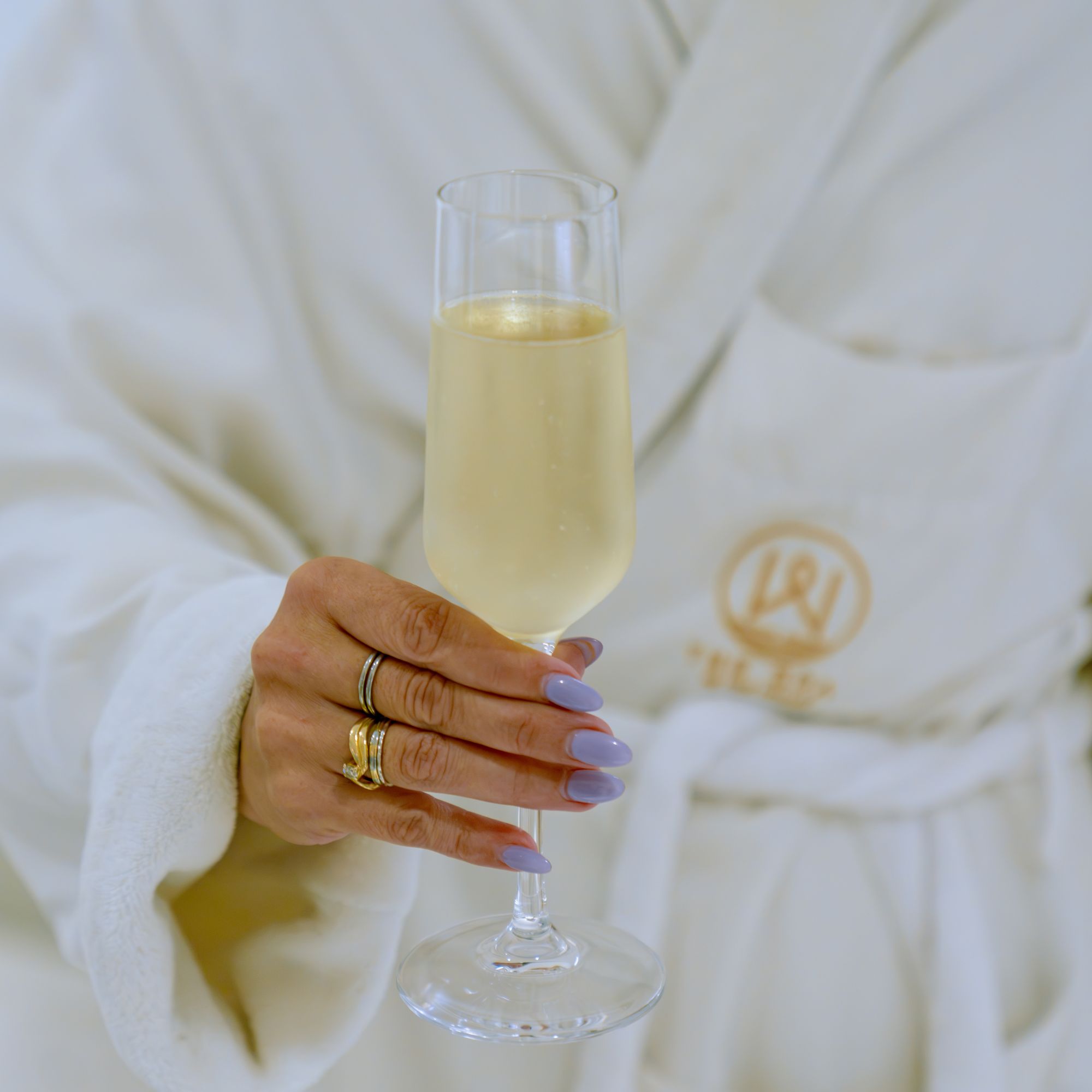 Close-up of a guest holding a flute of sparkling wine while wearing a white spa robe at InterContinental Washington D.C. - The Wharf.