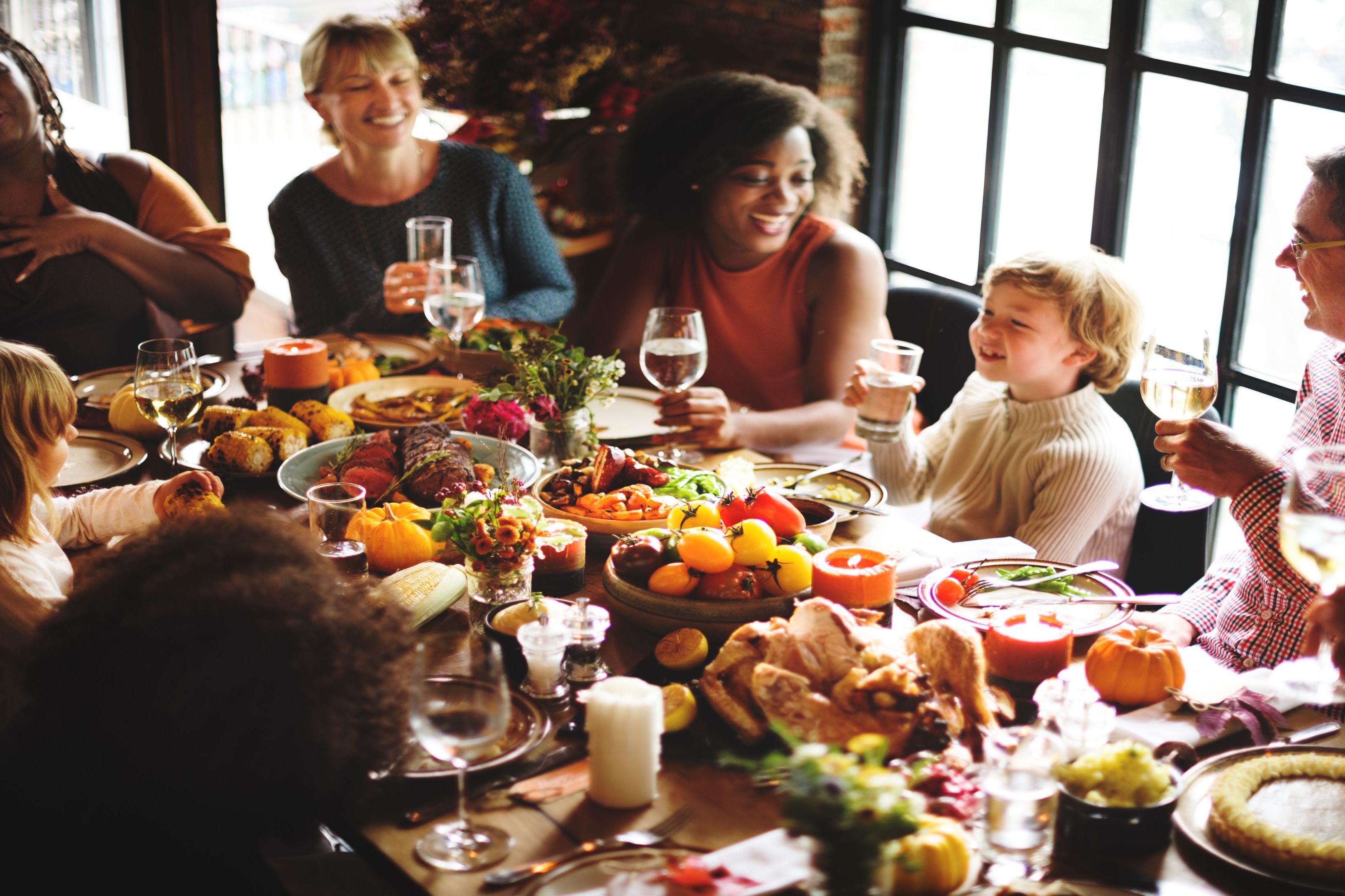 Family and friends gathered around a Thanksgiving table with turkey, seasonal dishes, and holiday décor.