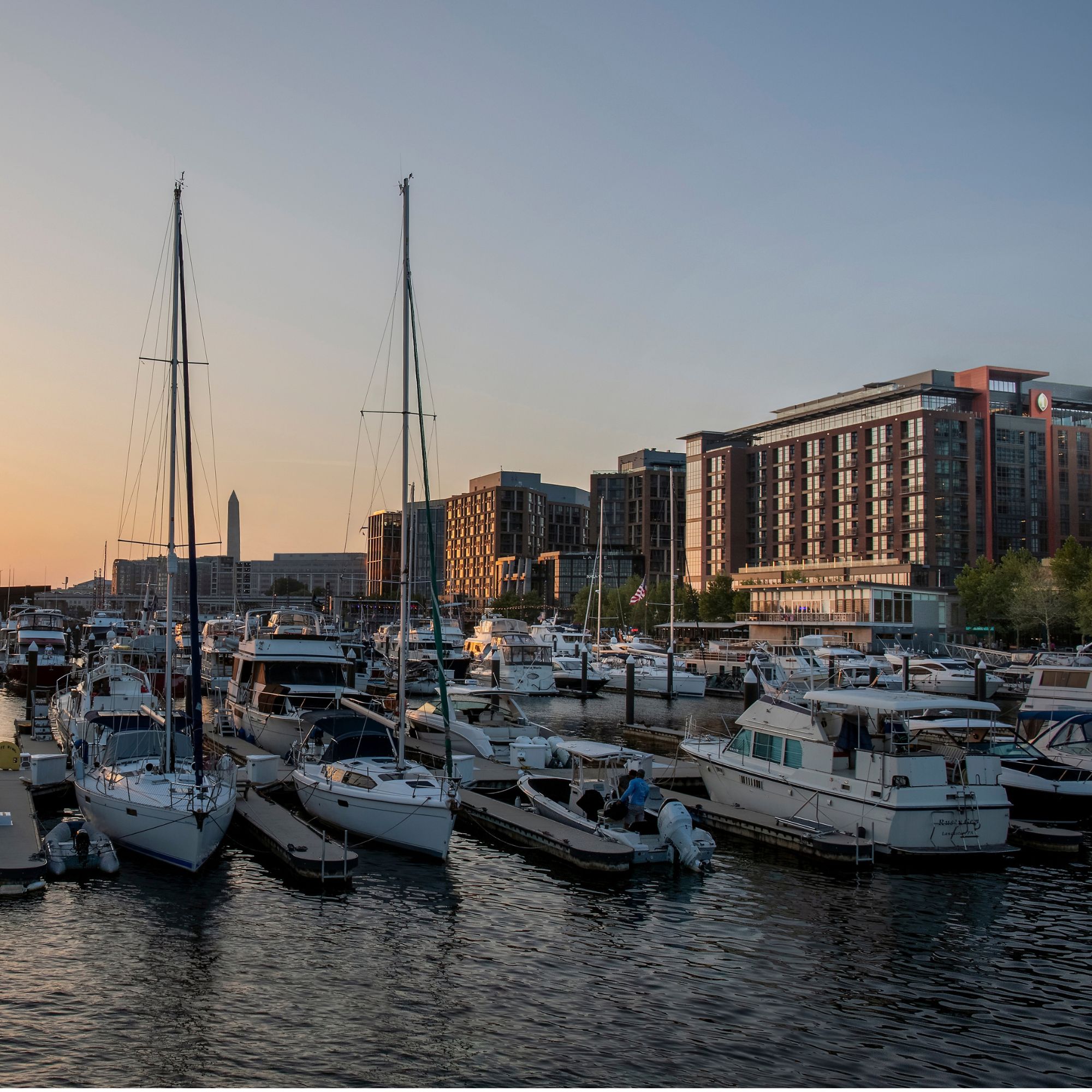 View of The Wharf marina with boats docked along the waterfront and InterContinental Washington D.C. - The Wharf at sunset.
