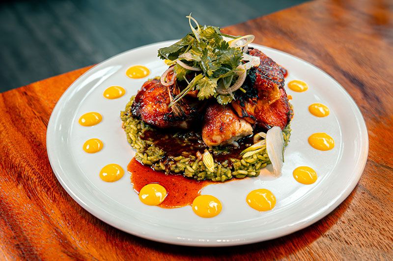 Chef-prepared entrée featuring glazed roasted chicken served over herbed rice with fresh greens and sauce, presented on a white plate at InterContinental Washington D.C. - The Wharf.
