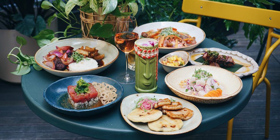 Various Latin dishes on blue table with yellow chairs