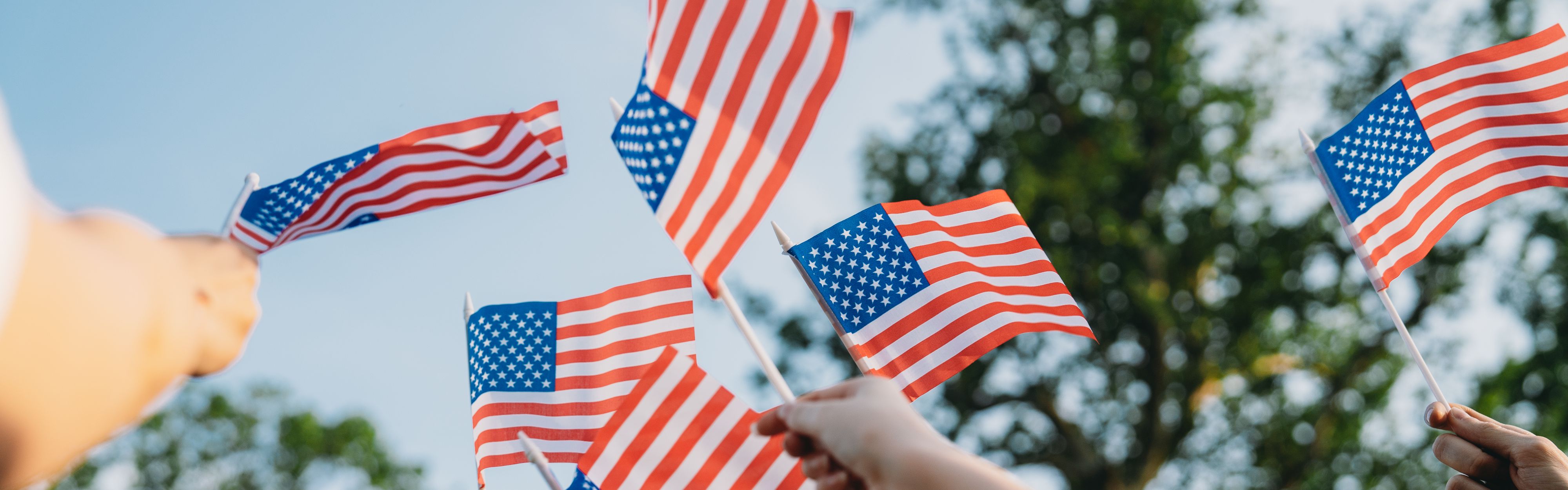Close up of small American flags being waved in the air.