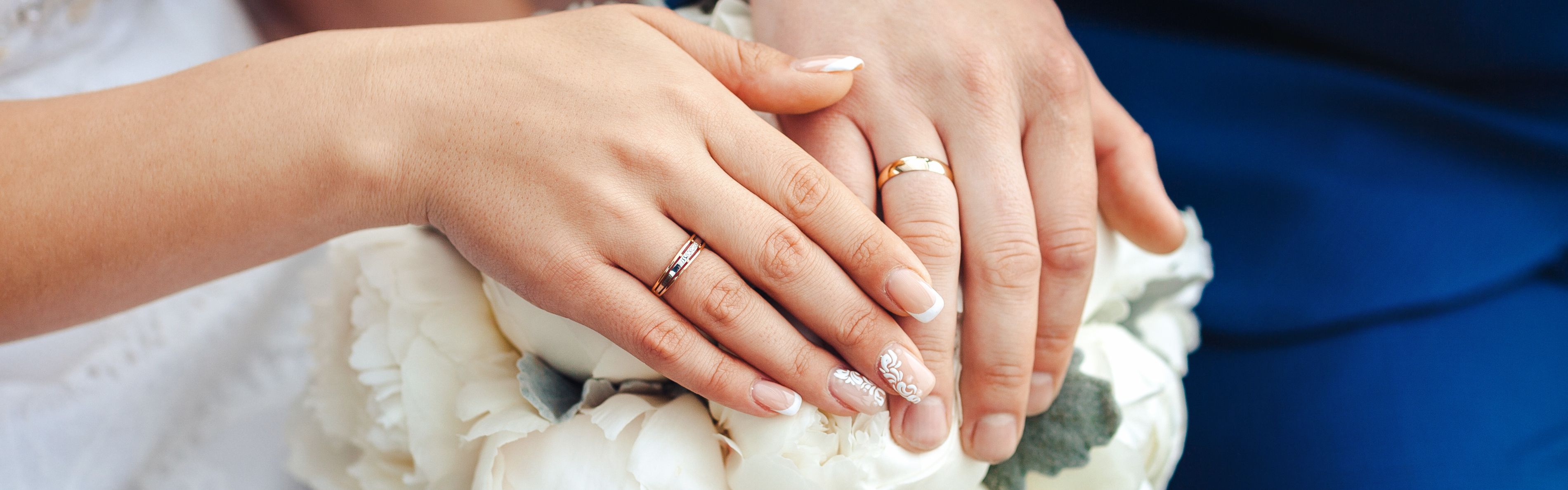 Wedding rings on bride and groom over bouquet