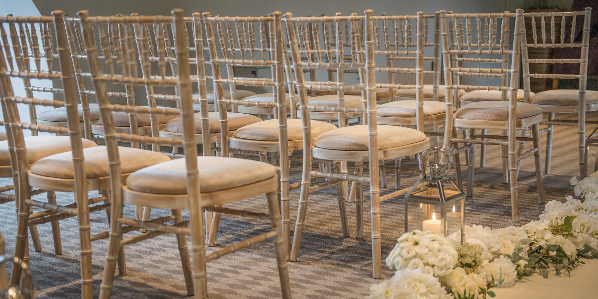 Wedding aisle with chairs, flower decor and lanterns with candles