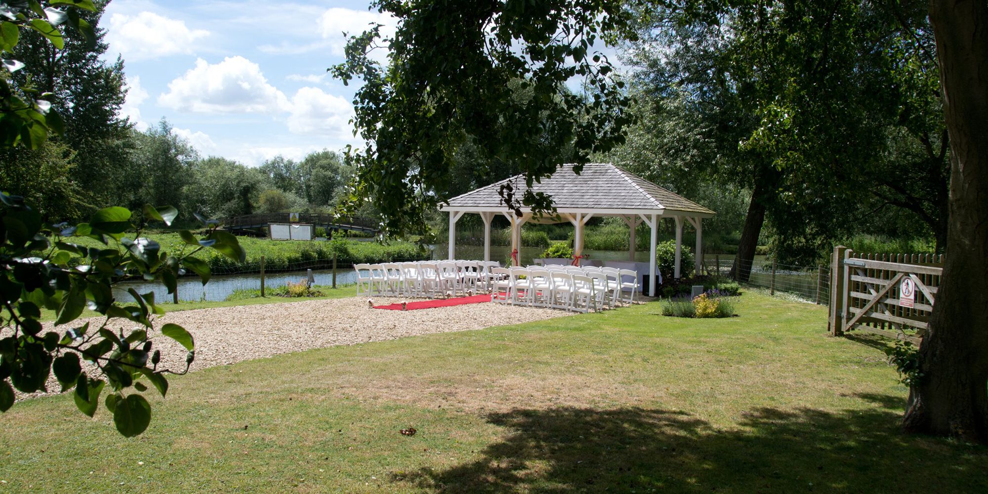 Outdoor pavilion with wedding aisle chairs by the Thames river and trees