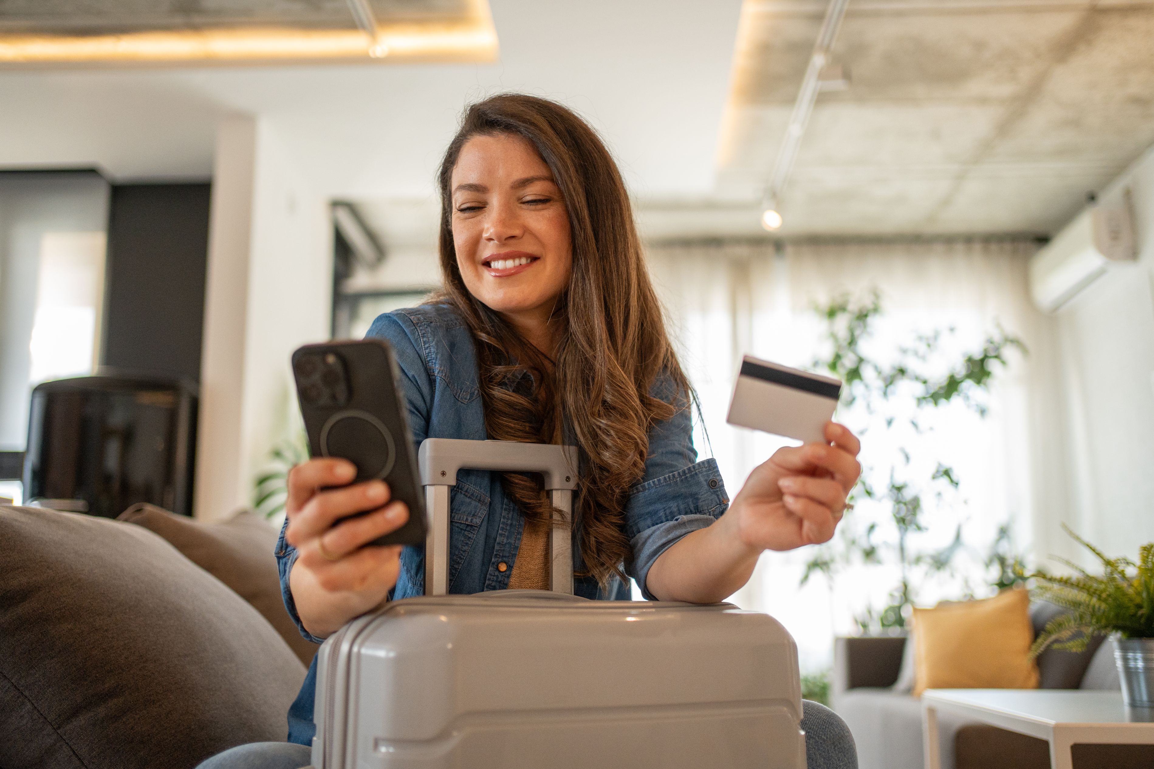 Woman holding her phone and credit card, booking a trip.