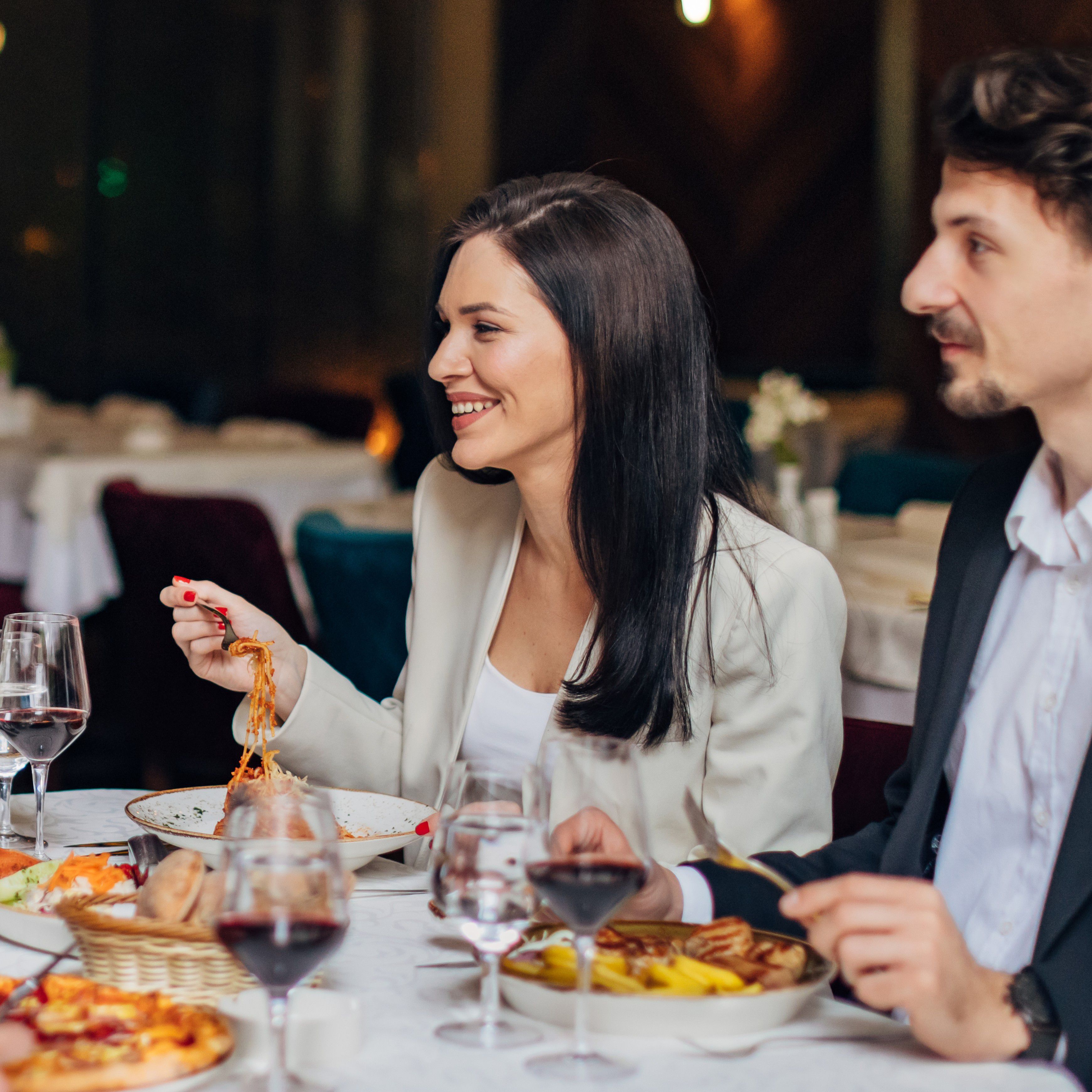 Woman eating pasta with friends