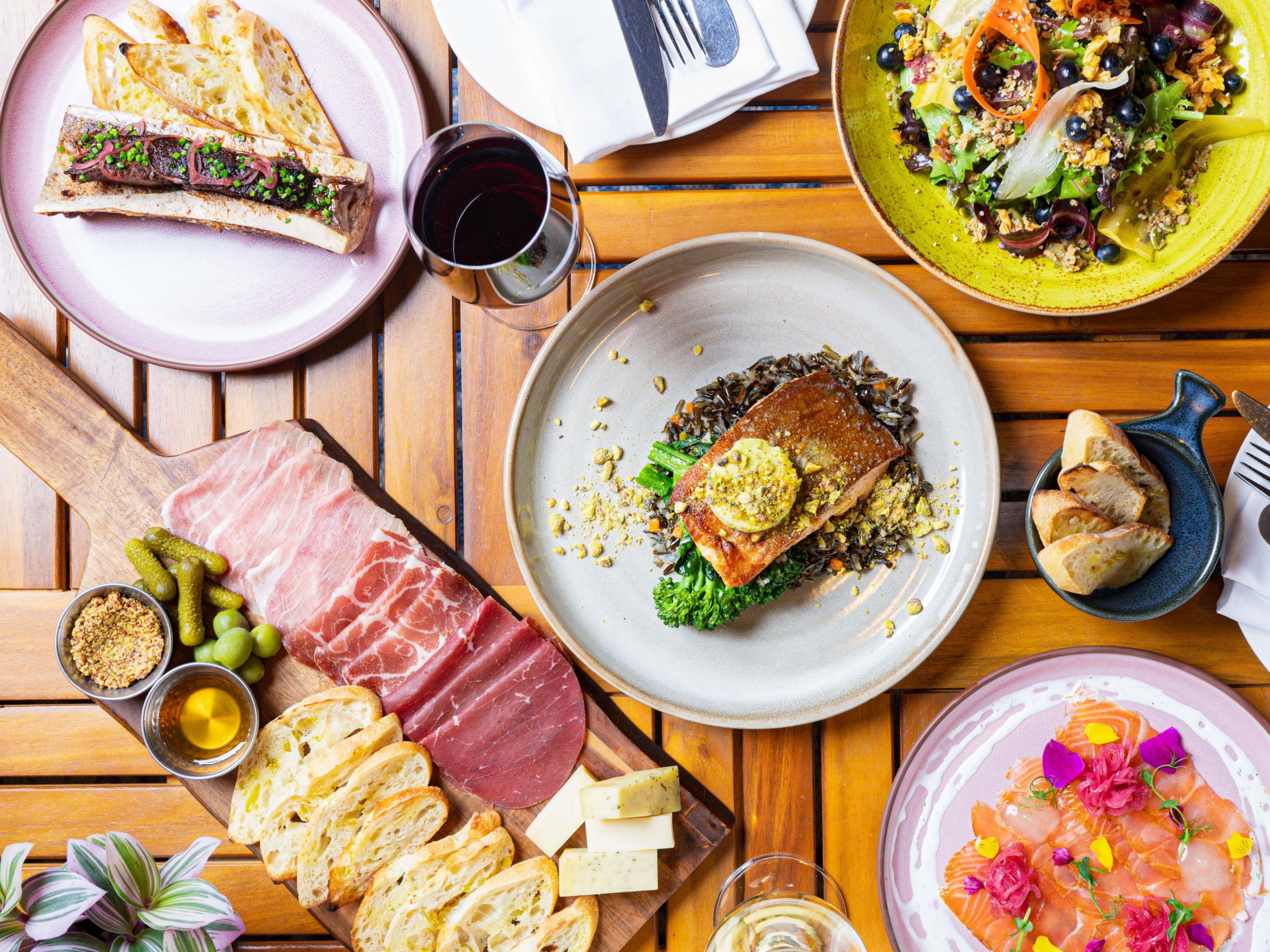 Assorted plated dishes, charcuterie, and wine on table