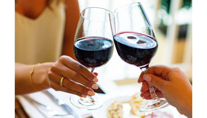 Two glasses of red wine raised in a toast.