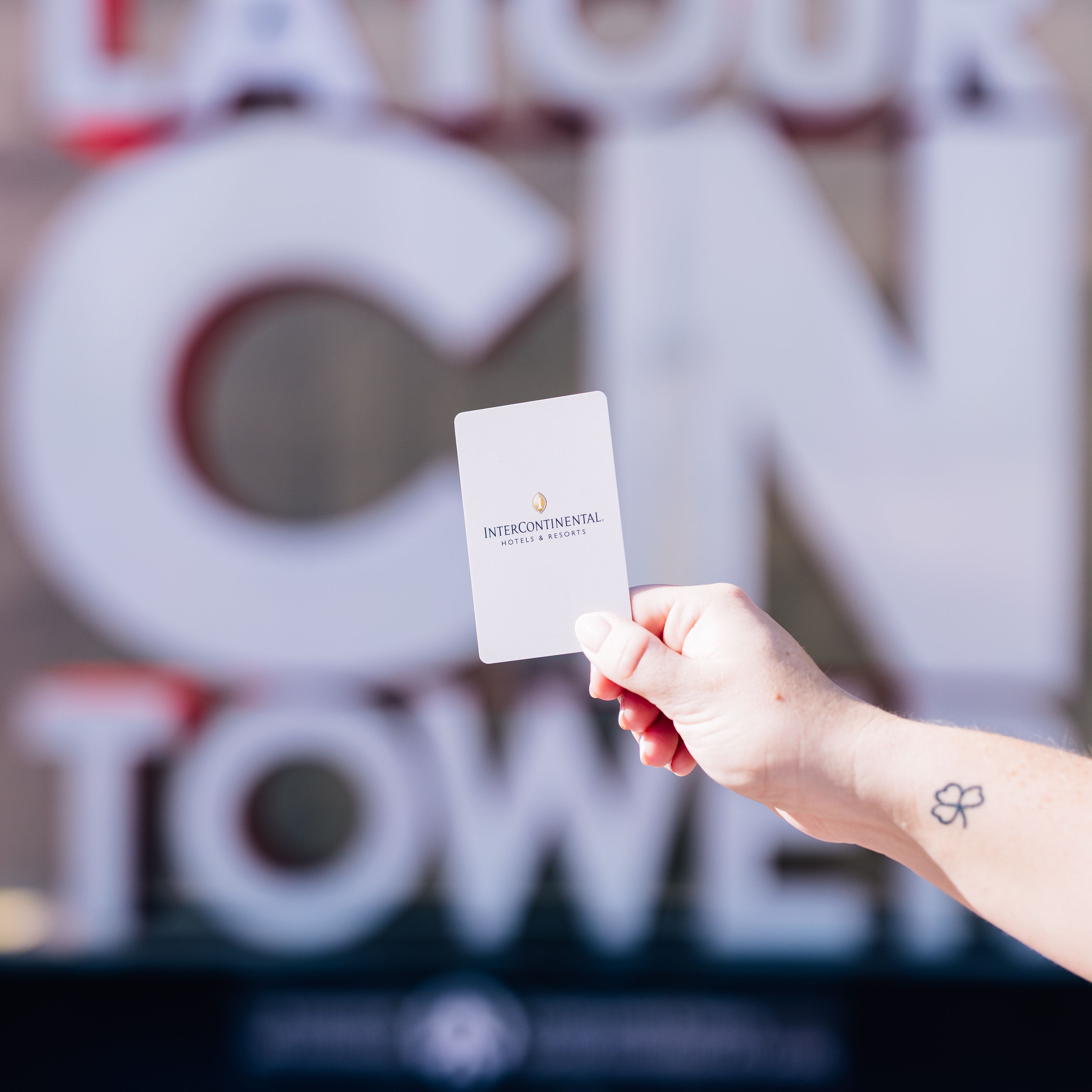 Guest holding hotel room card up in front of attraction.