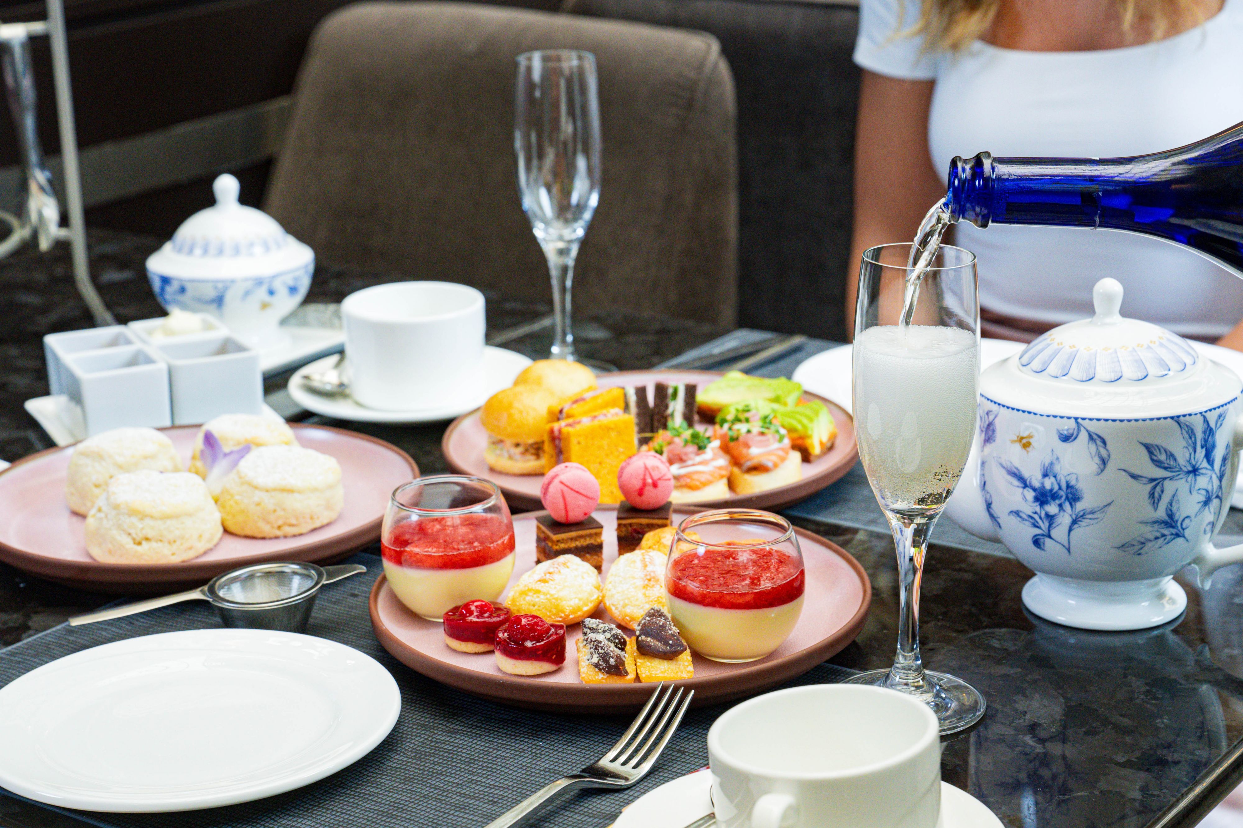 Afternoon tea service with pastries, sandwiches, and sparkling wine