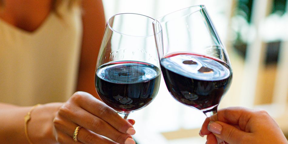 Two glasses of red wine being toasted.