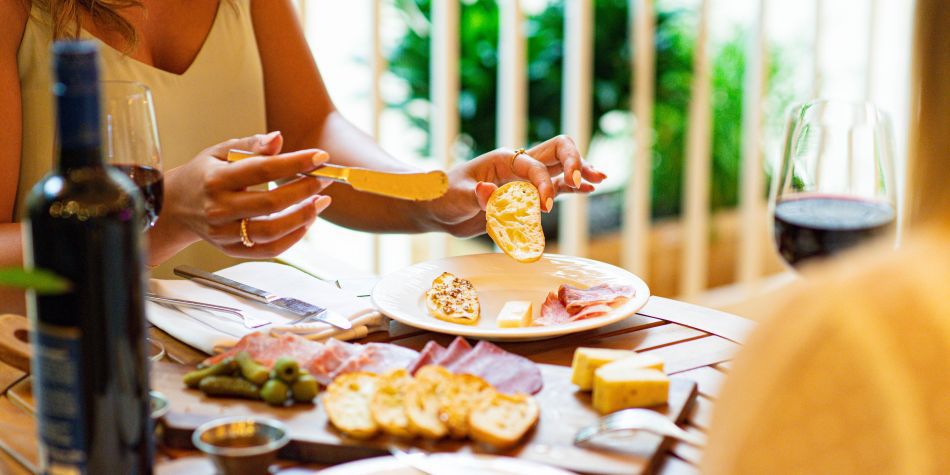 Charcuterie board with wine and bread at outdoor dining table.