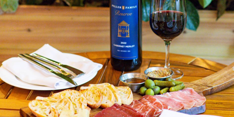Cured meats, olives, and bread with wine on outdoor table.