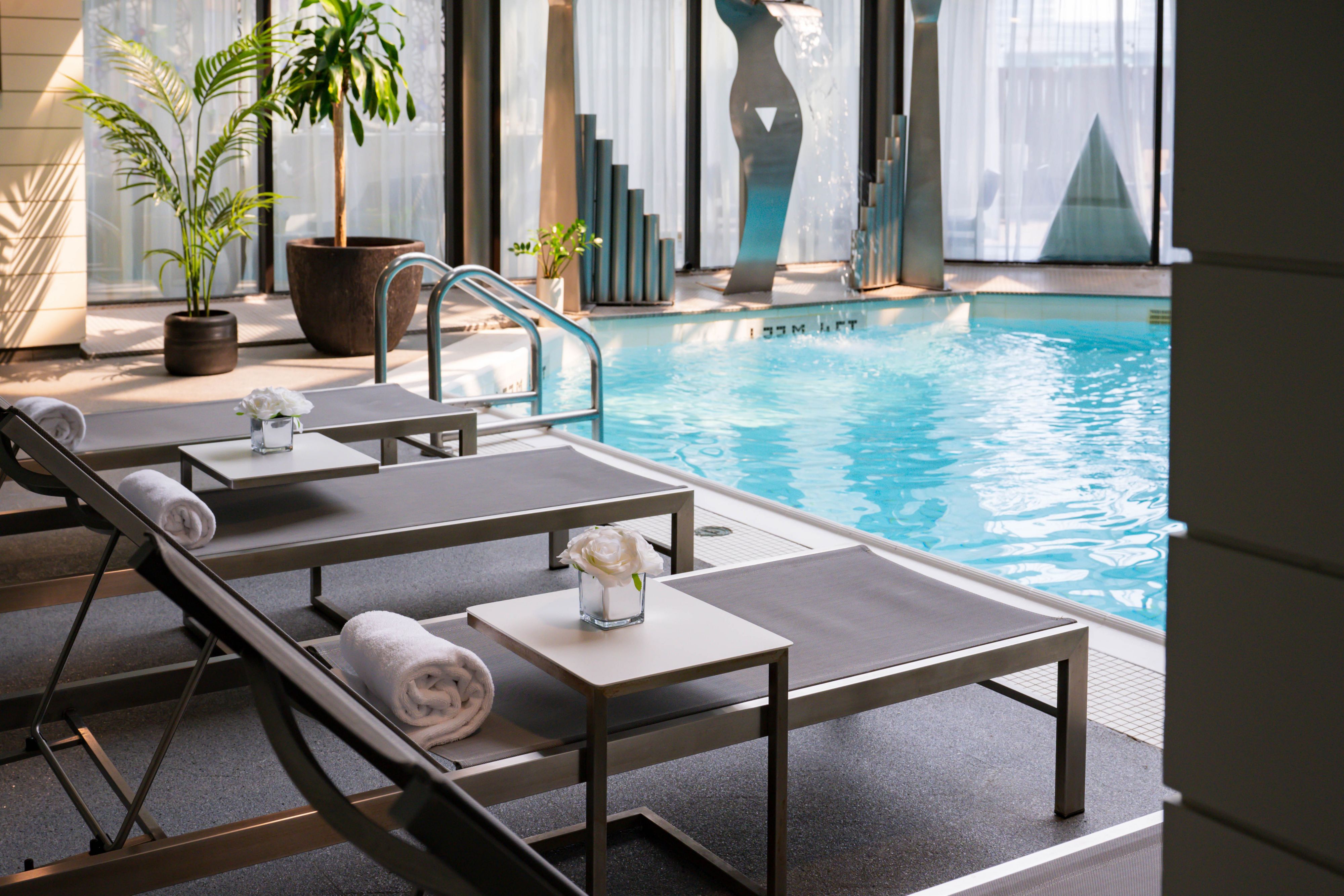 Indoor pool with lounge chairs, towels, and plants