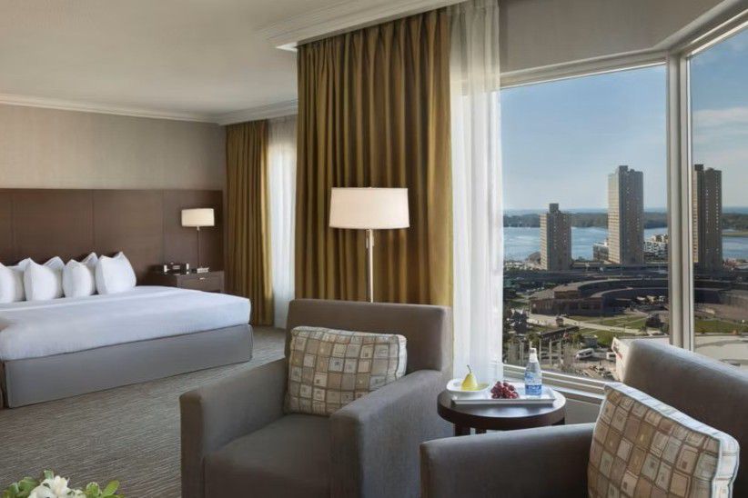 Spacious hotel guest room with seating area and city views.