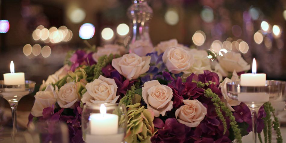 Floral centerpiece with roses and candles on reception table