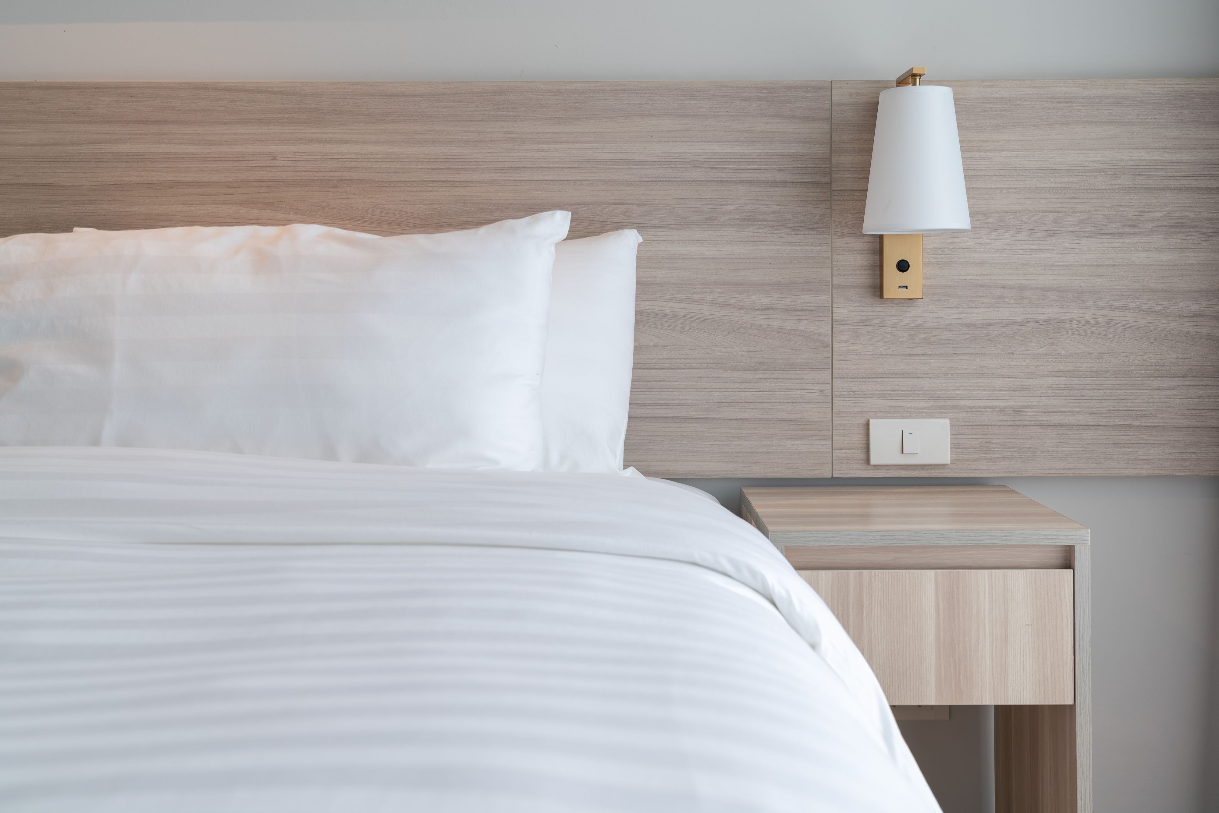 Chambre d'hôtel avec lit, applique murale et table de chevet