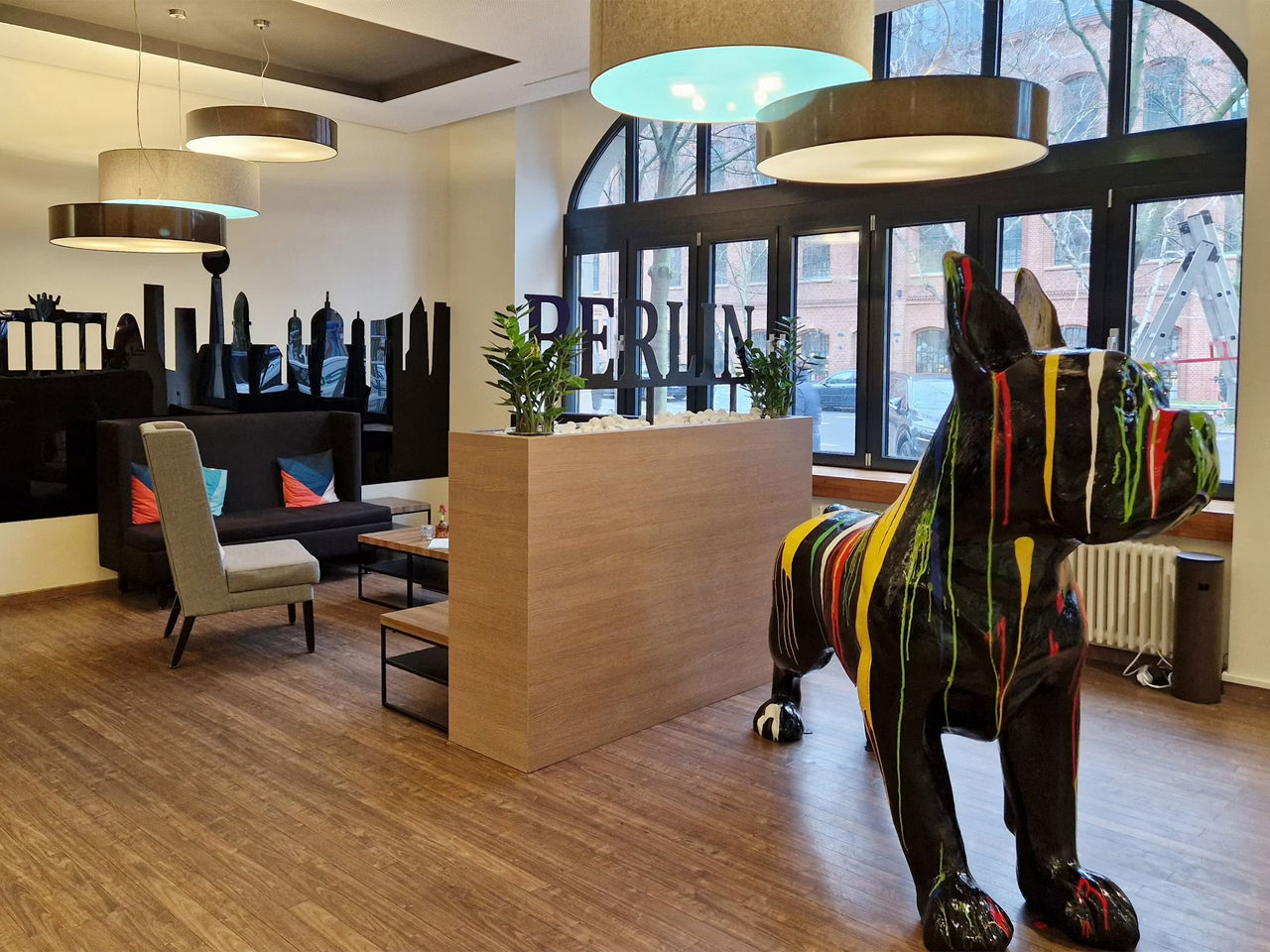 Large painted black dog statue with seating area and skyline cutout on wall